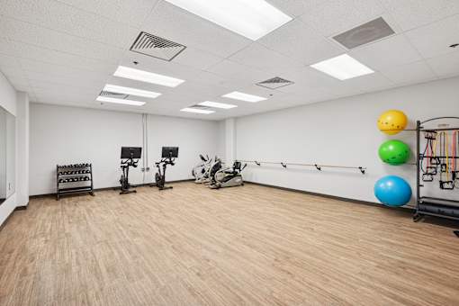A gym with exercise equipment and a wall of windows.