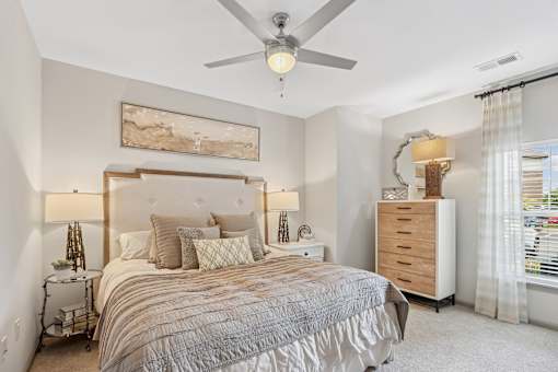 A bedroom with a large bed, a dresser, and a ceiling fan.