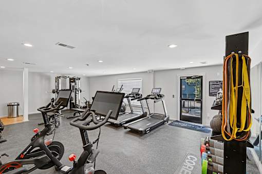 A gym with a row of stationary bikes and a treadmill.