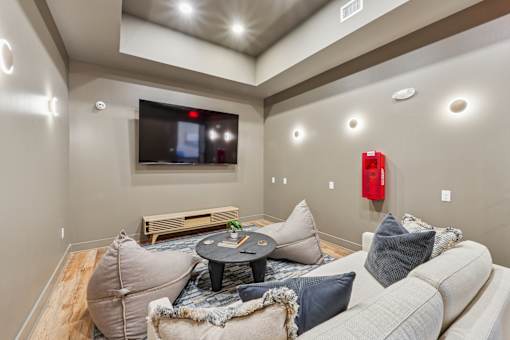 A living room with a white couch and a flat screen TV mounted on the wall.
