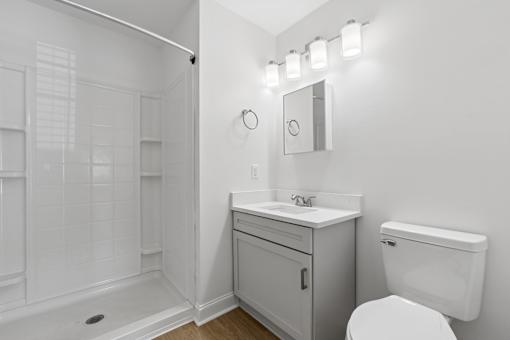 A white bathroom with a toilet, sink, and shower.