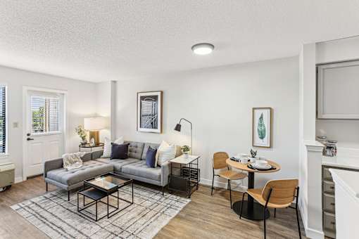 A living room with a grey couch, a coffee table, and a dining table with chairs.