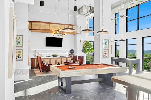A billiard table is in the middle of a room with a television and a couch.