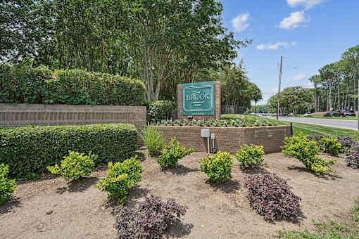 A sign that says Brooks is surrounded by green shrubbery.