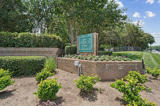 A sign that says "BROOK" is in front of a hedge.