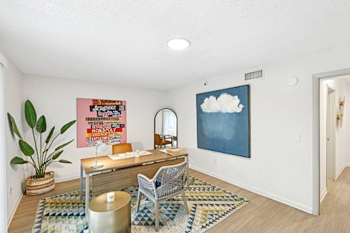 A room with a desk, chair, and a potted plant.