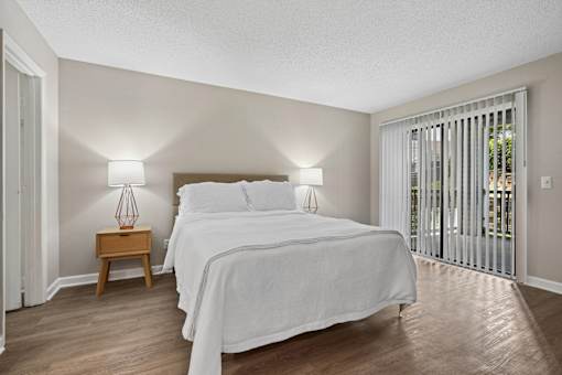 A bedroom with a large bed and a wooden nightstand.