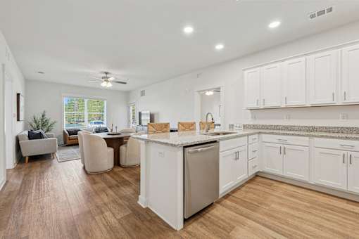 A kitchen with white cabinets and a wooden floor.