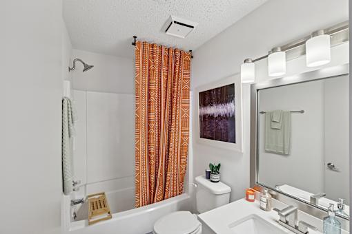 A bathroom with orange curtains and a white toilet.