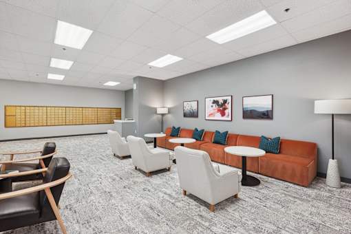 A waiting room with a sofa, chairs, and pictures on the wall.