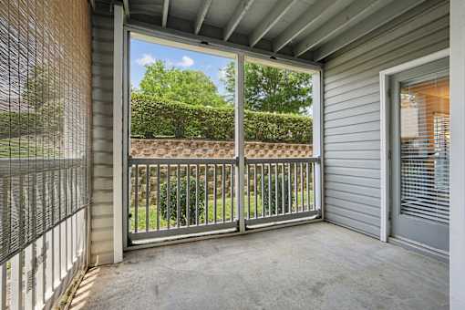A patio with a metal railing and sliding glass doors leading to a backyard.
