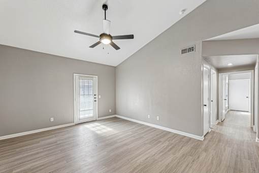 A room with a ceiling fan and wooden flooring.