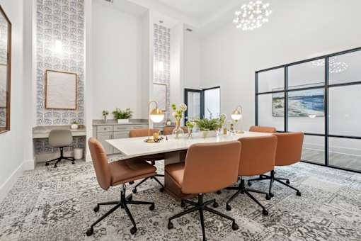 A conference room with a long table surrounded by orange chairs.