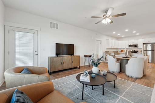 A living room with a brown sofa, a black coffee table, and a television.