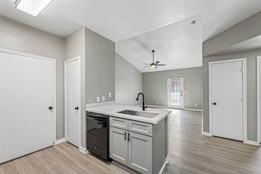 A kitchen with a fan on the ceiling and a sink with a faucet.