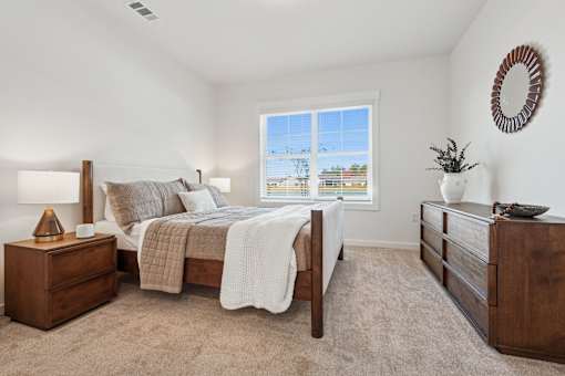 A bedroom with a large bed, a nightstand, and a dresser.