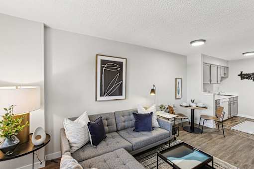 A living room with a grey couch, a coffee table, and a painting on the wall.