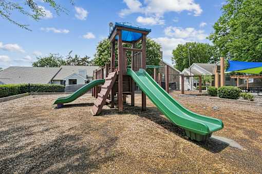 A playground with a green slide and a blue roofed structure.
