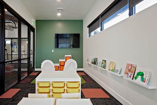 A room with a green wall and a white shelf with books on it.