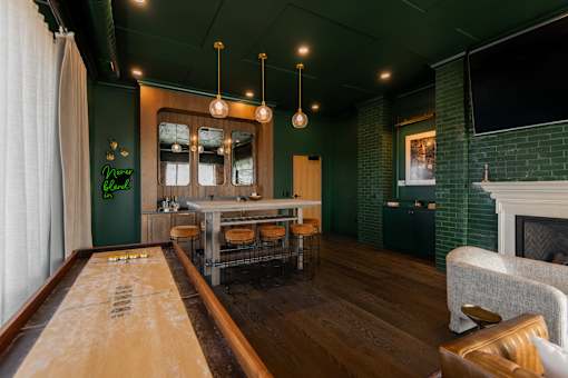 A shiny wooden table is in the middle of a room with a green wall.