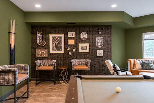 A billiard table is in the middle of a room with green walls.