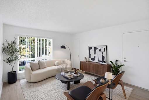 A living room with a white couch, a coffee table, and a painting on the wall.