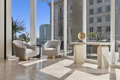 A room with a table and chairs with a view of a building outside.