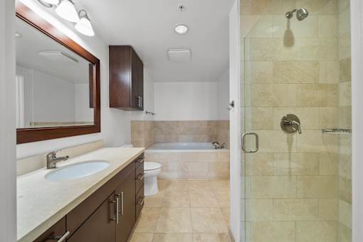 A bathroom with a sink, mirror, toilet, and shower.