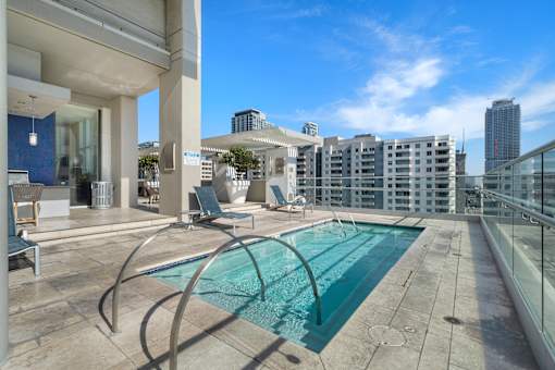 A modern pool area with a glass railing and a view of the city.