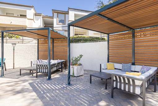 A patio with a striped couch and a table with a potted plant on it.