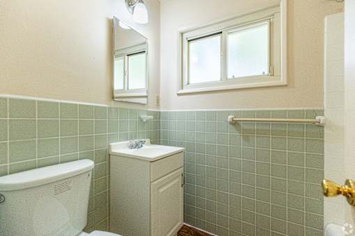 A white toilet sits next to a white sink in a bathroom.