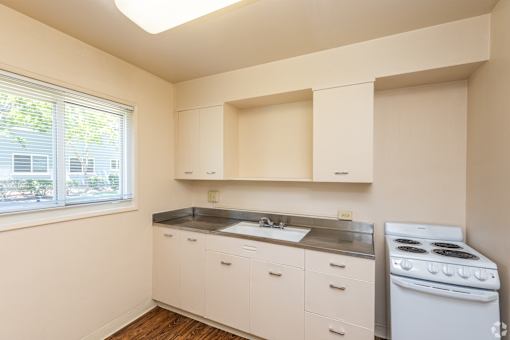 A small kitchen with white cabinets and a stove.