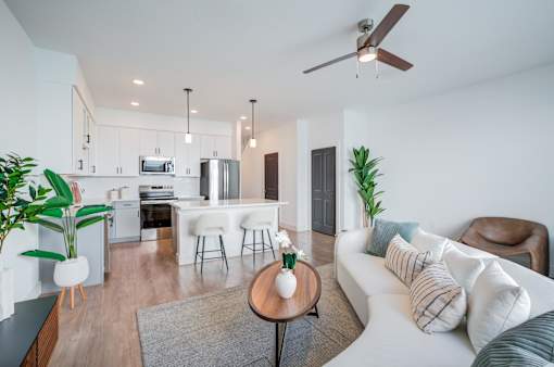 A modern living room with a kitchen in the background.