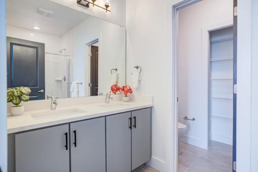 A bathroom with a double sink vanity and a mirror above it.