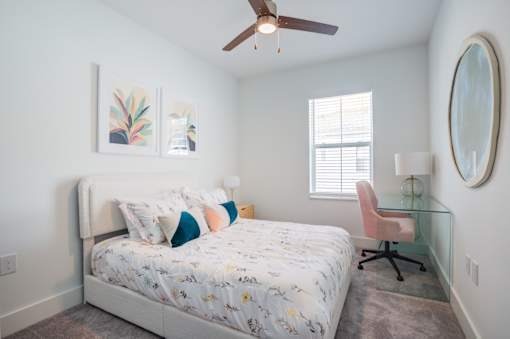 A bedroom with a bed, chair, and two framed pictures on the wall.