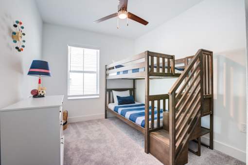 A bedroom with a bunk bed and a ceiling fan.
