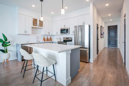 A modern kitchen with white cabinets and a wooden floor.