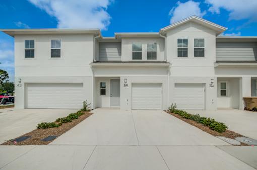 A white two story house with a garage door and windows.