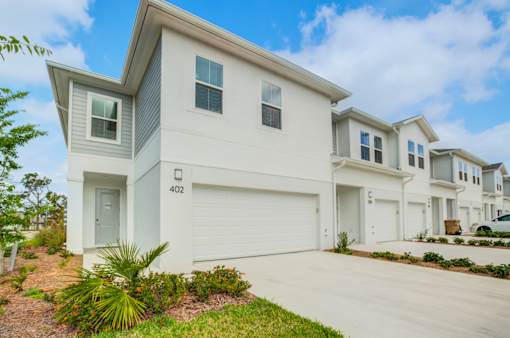 A white house with a grey roof and a garage door.