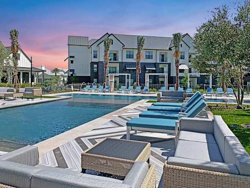 A modern poolside area with lounge chairs and a building in the background.