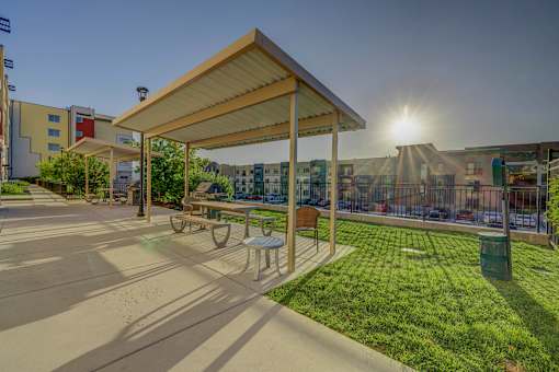 A sunny day at the park with a pavilion and benches.