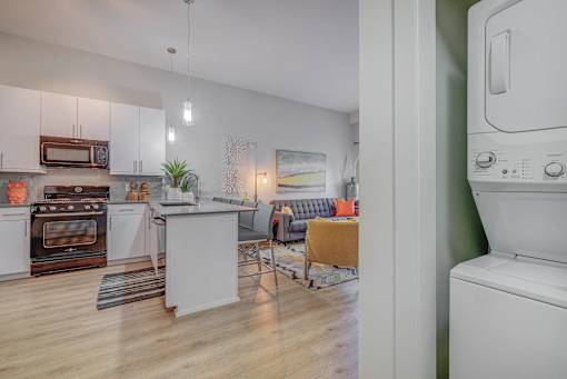 A modern kitchen with white appliances and wooden floors.