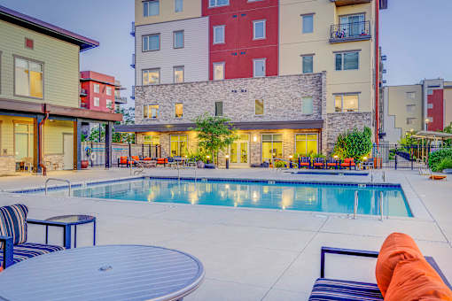 A swimming pool surrounded by a patio with chairs and a table.