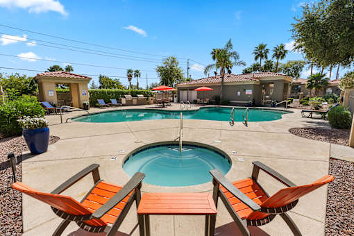 A pool surrounded by orange chairs and palm trees.