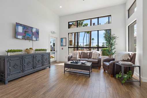 A living room with a grey sofa set and a flat screen TV mounted on the wall.