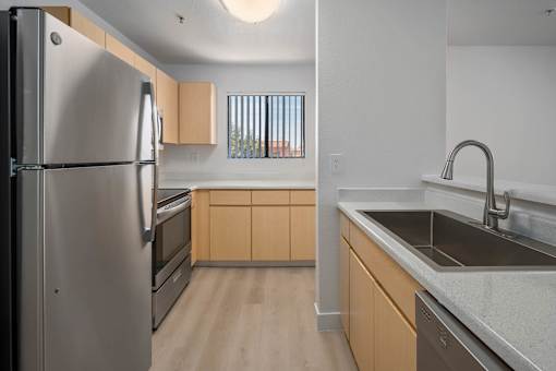 A kitchen with a refrigerator, oven, and sink.