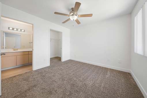A room with a ceiling fan and carpeted floor.