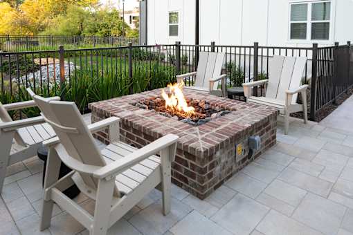 A fire pit with a fire burning in it surrounded by chairs.