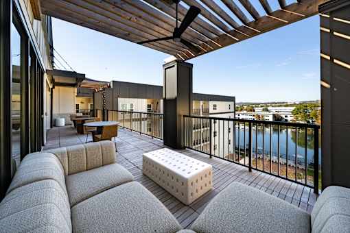 A modern balcony with a white couch and a wooden pergola.