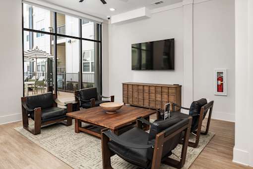 A modern living room with a wooden coffee table and black leather chairs.